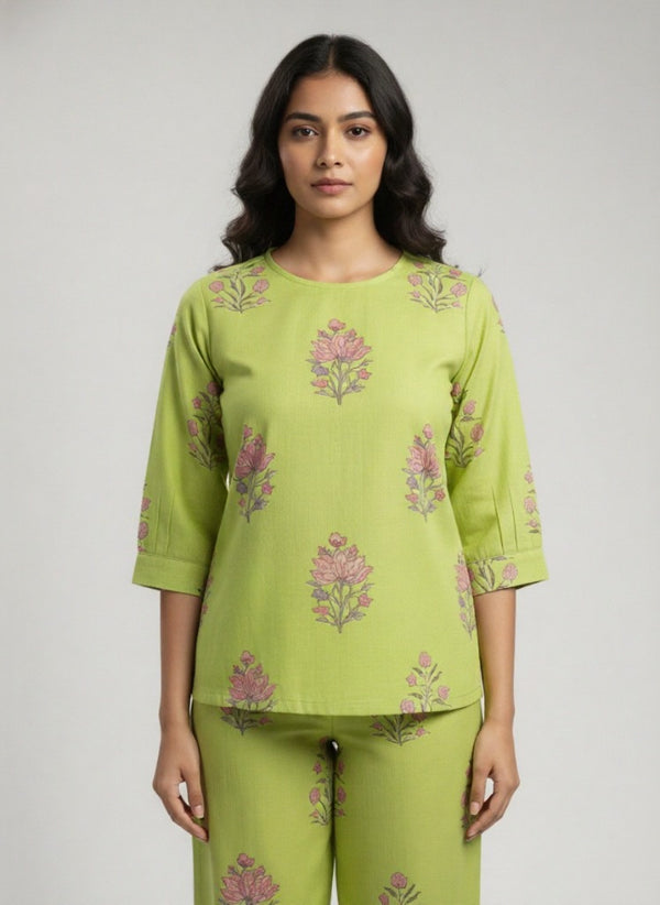 Model sitting and standing in a modern living room wearing a House of Fabera lime green floral print tunic and trouser set.